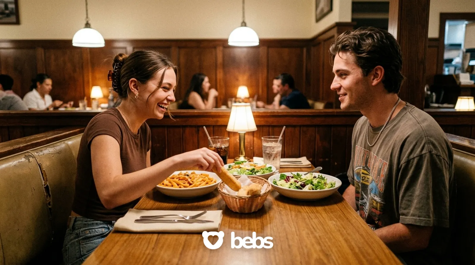 Young couple sharing breadsticks and pasta in a cozy booth on a casual Olive Garden first date in LA, booked with the Bebs dating app